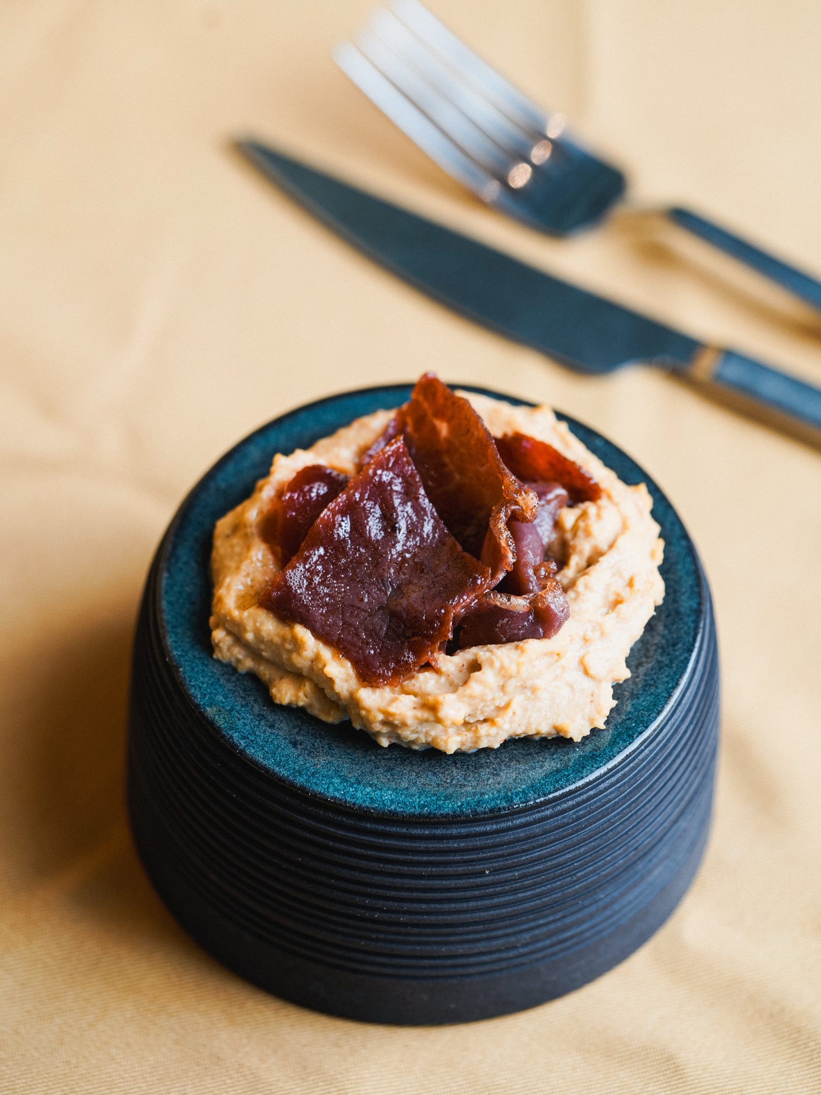 Humus ve pastırma servis edilmiş nervürlü koyu mavi ayaklı tabak
